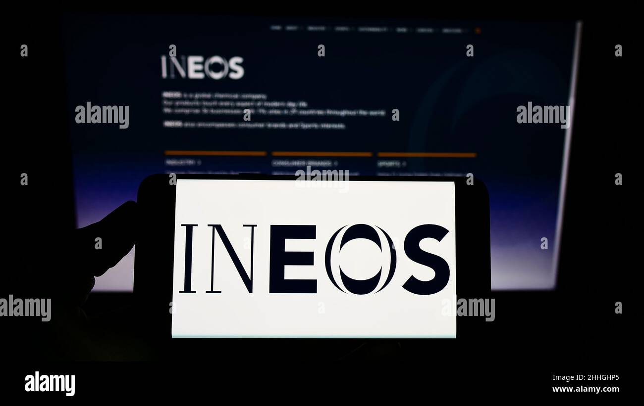 Personne tenant un smartphone avec le logo de la société britannique de produits chimiques INEOS Group Ltd. À l'écran devant le site Web.Mise au point sur l'affichage du téléphone. Banque D'Images