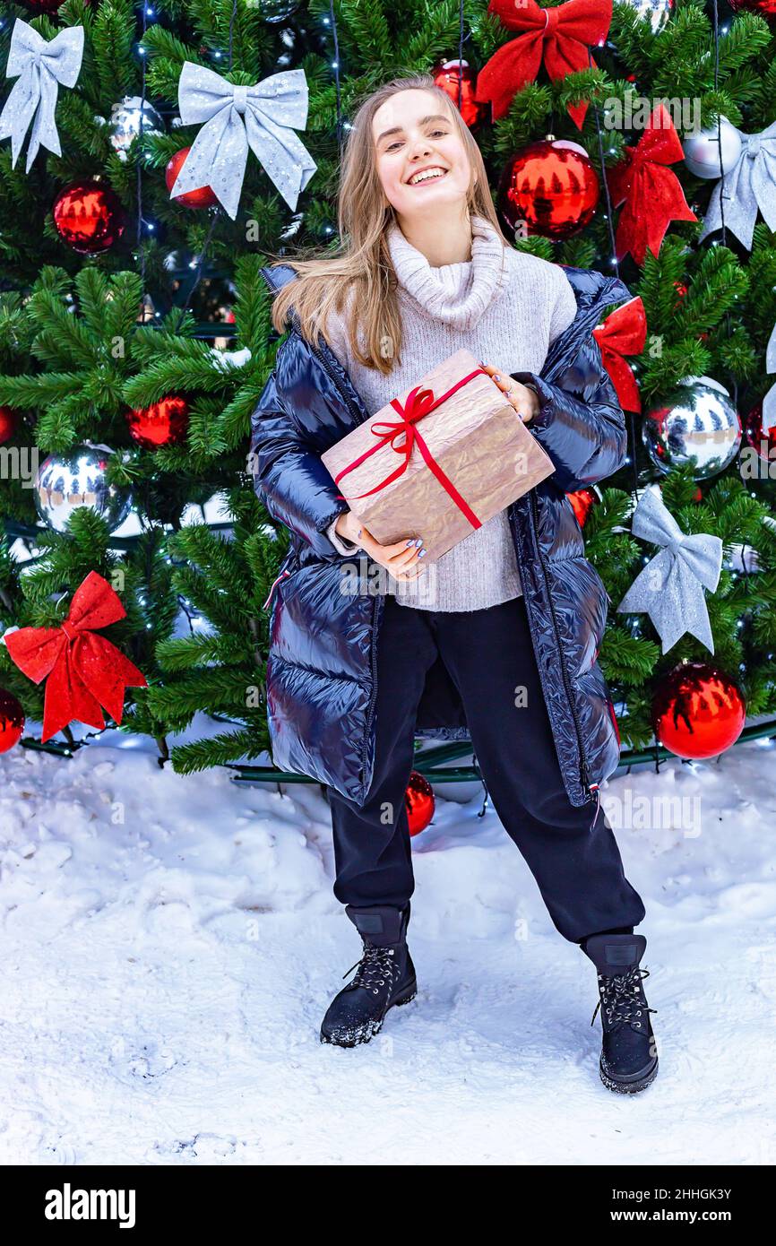Bonne fille blonde souriante avec cadeau de Noël.Une adolescente attrayante d'origine caucasienne avec un cadeau dans ses mains sur le fond du CH Banque D'Images