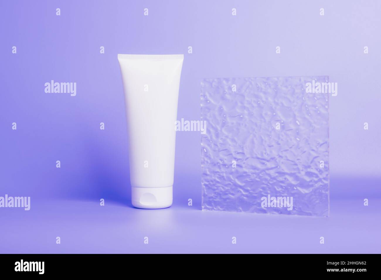 Produit cosmétique dans un tube, contenant blanc sur fond violet.Shampooing, crème pour les mains, dentifrice emballage blanc Banque D'Images