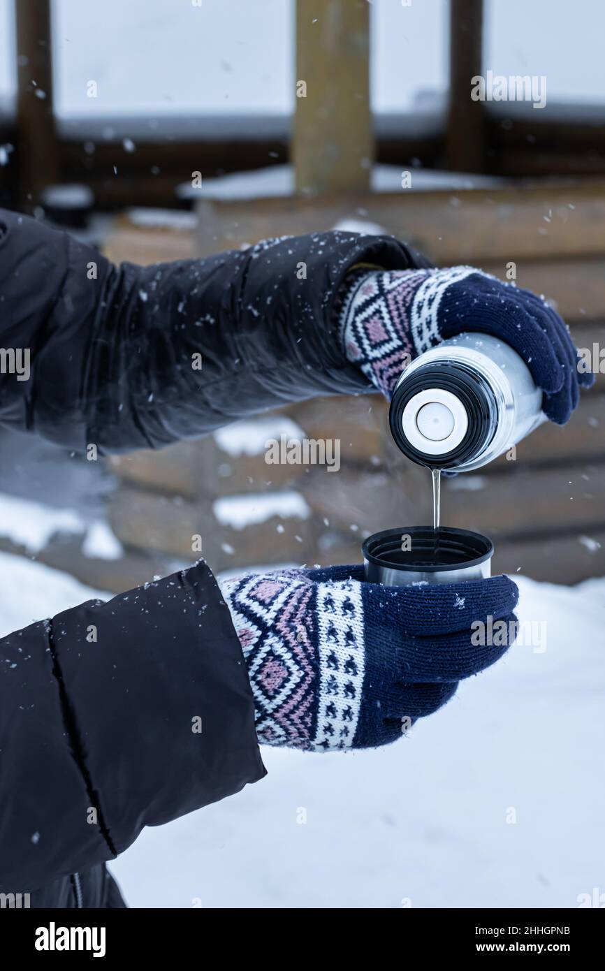 une femme en poids verse du thé dans une tasse d'un thermos.Photo de haute qualité Banque D'Images