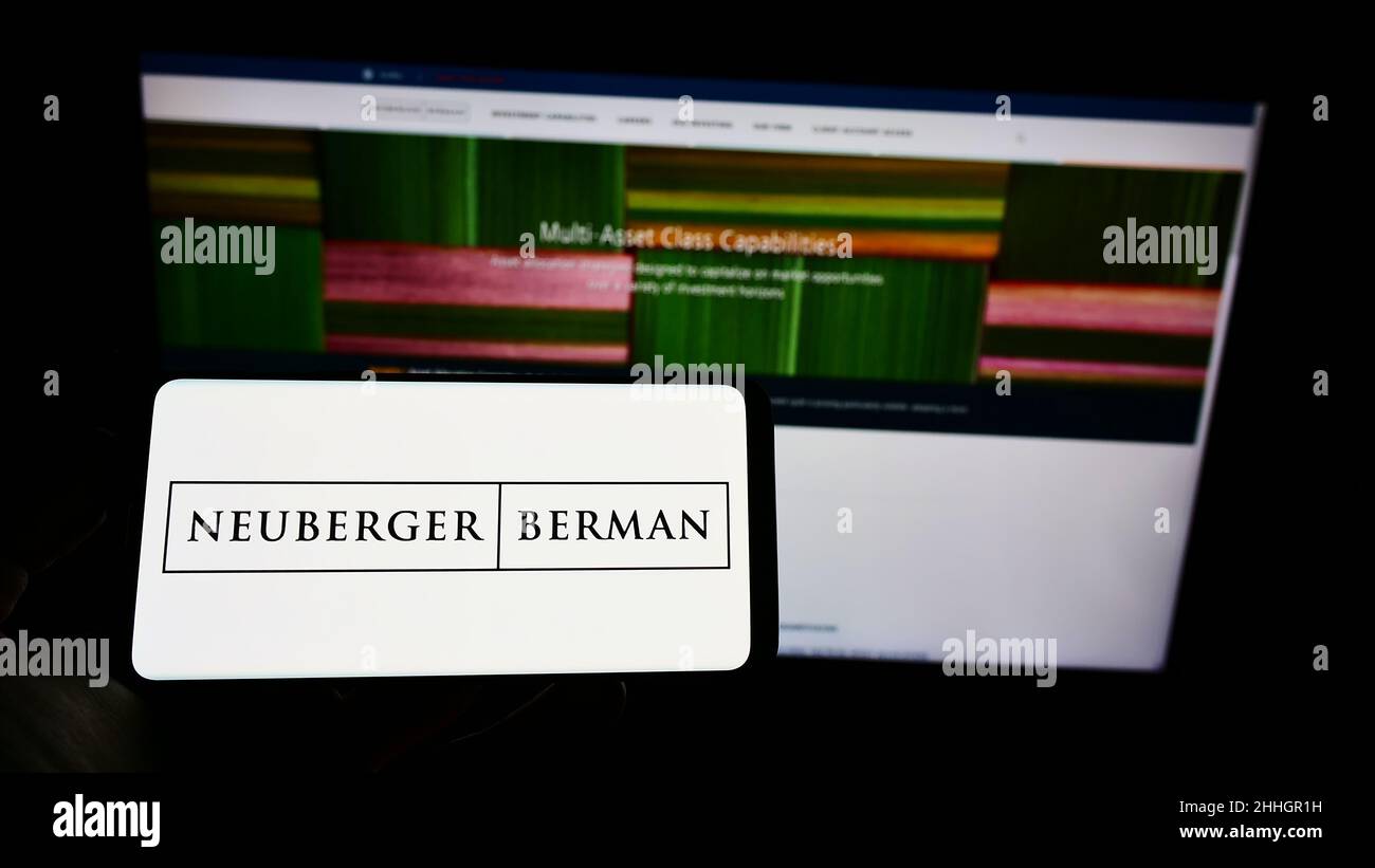 Personne tenant un téléphone portable avec le logo de la société d'investissement américaine Neuberger Berman Group LLC à l'écran en face de la page Web.Mise au point sur l'affichage du téléphone. Banque D'Images