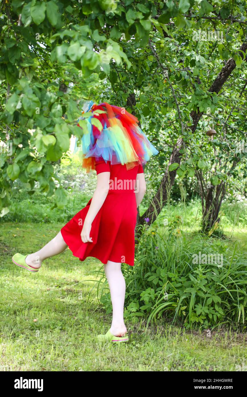 Adorable fille en robe arc-en-ciel colorée sur sa tête jouant à l'extérieur Banque D'Images