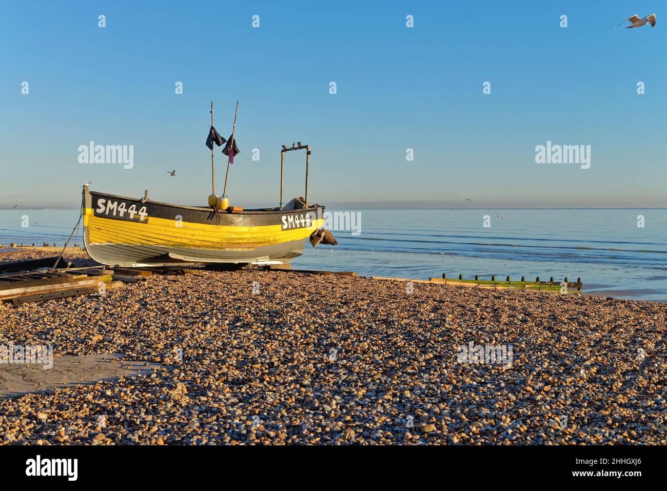 Un bateau de pêche traditionnel sur l'East Beach à Worthing lors d'une journée hivernale ensoleillée avec une mer calme en arrière-plan à l'ouest du Sussex Angleterre Royaume-Uni Banque D'Images