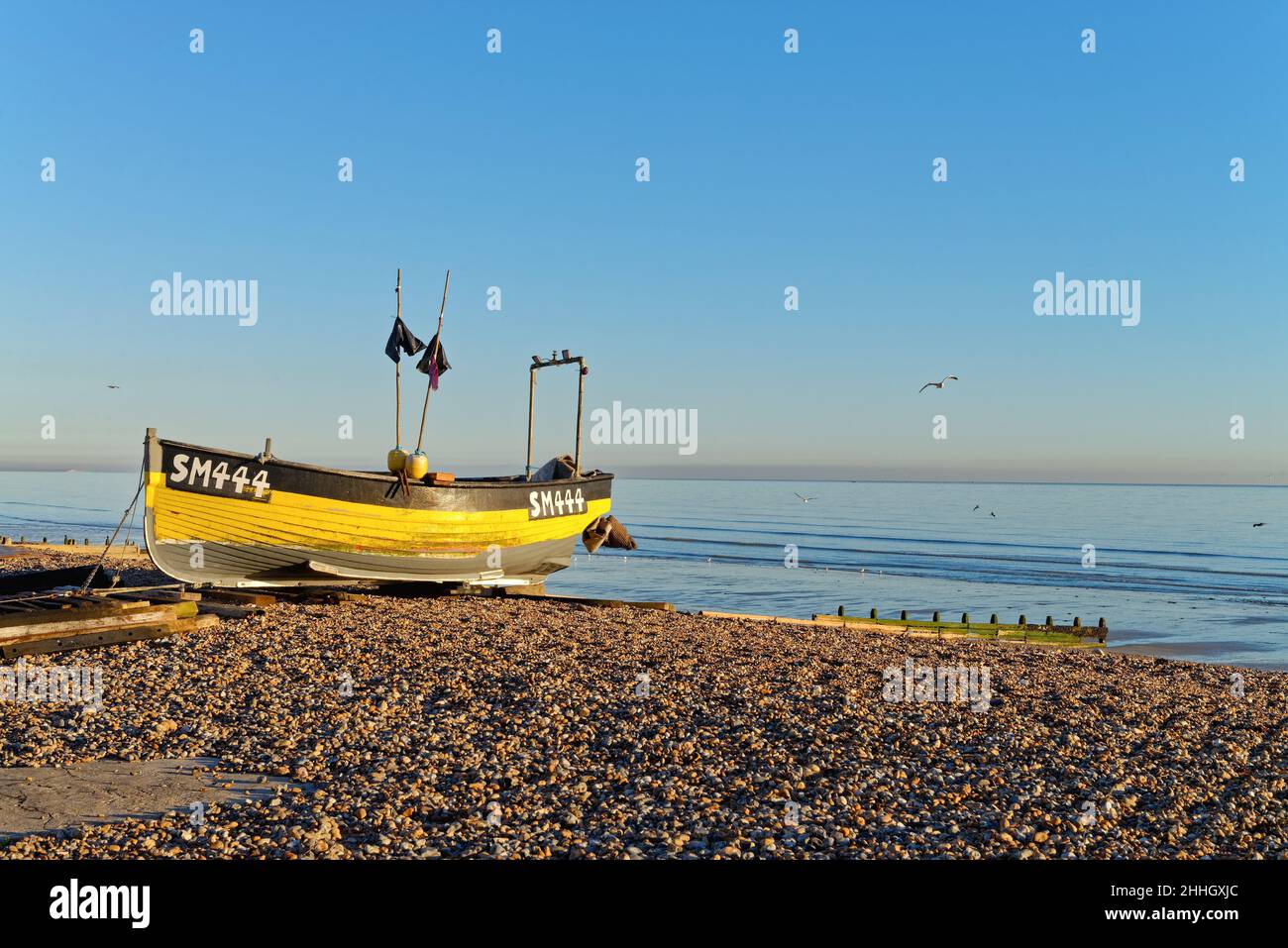 Un bateau de pêche traditionnel sur l'East Beach à Worthing lors d'une journée hivernale ensoleillée avec une mer calme en arrière-plan à l'ouest du Sussex Angleterre Royaume-Uni Banque D'Images
