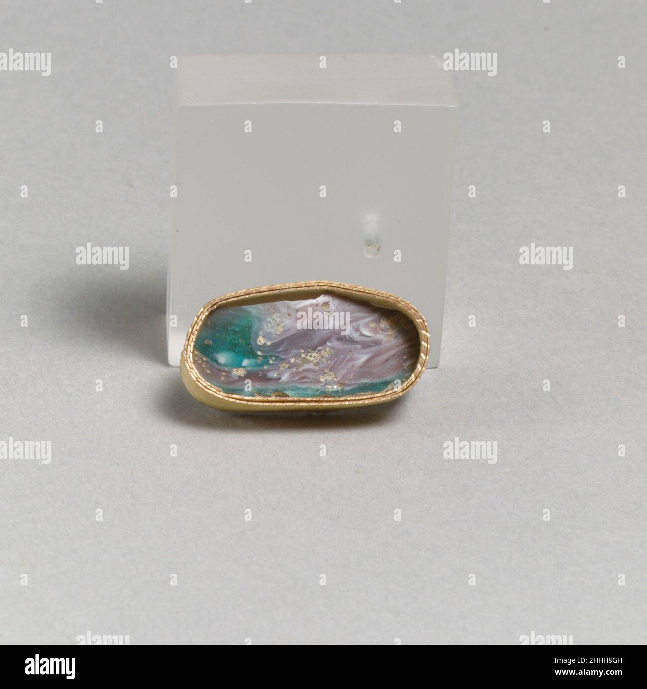 Fragment de mosaïque de verre fin du 1st siècle C.-B.–début du 1st siècle A.D. Roman fragment de base à parois minces.violet translucide, bleu turquoise et blanc opaque.bord biseauté vers l'extérieur; côté légèrement convexe courbé, incliné vers l'intérieur.motif en mosaïque formé de sections polygonales de deux cannes :l'un dans un sol bleu avec des tiges blanches, et l'autre dans un sol violet avec de nombreuses éclaboussures blanches.Les deux cannes sont très déformées.extérieur poli; piqûres et altération des bulles de surface à l'extérieur; morcellement, piqûres et altération brun crémeux à l'intérieur, au bord de la base et aux bords dentelés.Fragment de mosaïque de verre 257204 Banque D'Images