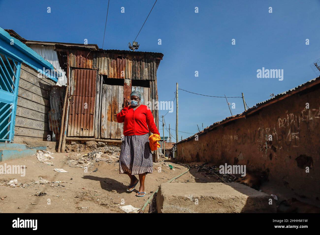Une femme portant un masque passe devant les bidonvilles de Kibera, Nairobi.Dans une maison où tout le monde est généralement amical et ravi de rencontrer des gens d'autres parties du pays et de différentes parties du monde,La vie est un peu surprenante en raison du niveau extrême de bonheur de la communauté malgré le taux élevé de pauvreté et le manque d'emplois.Une bouée de sauvetage des personnes vivant dans les bidonvilles dans les structures de logement pauvres dépend fortement d'emplois à faible revenu pour soutenir leurs besoins quotidiens et cela n'est possible que lorsque des habitants de différentes parties de la communauté rejoignent h Banque D'Images