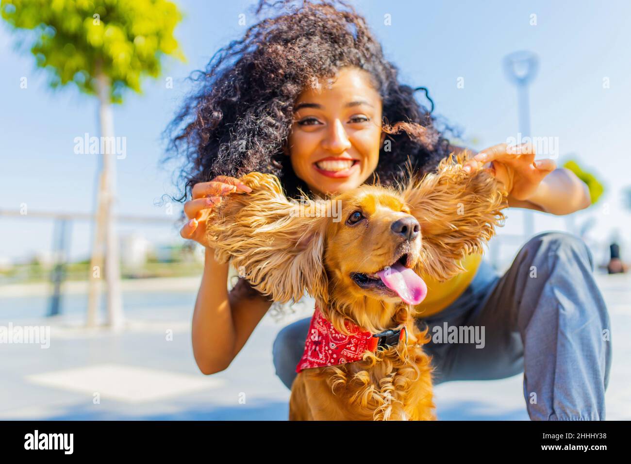 jeune heureux boucles cheveux femme jouant avec un coq américain sur la plage ruelle au soleil lumière palmiers fond Banque D'Images