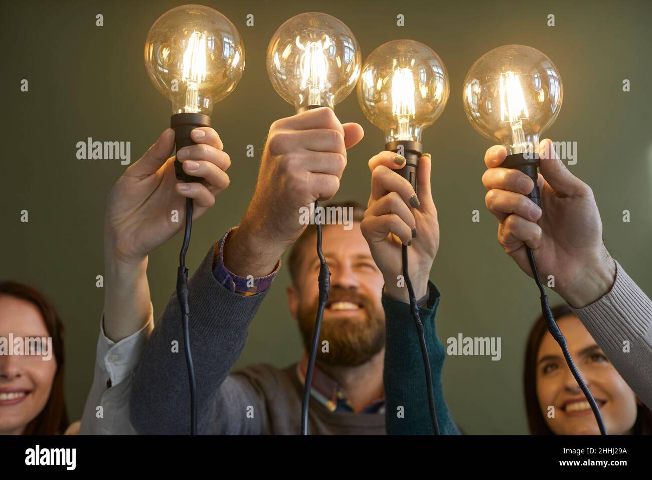 Équipe de créateurs heureux tenant des ampoules comme symbole d'idées et d'innovations Banque D'Images