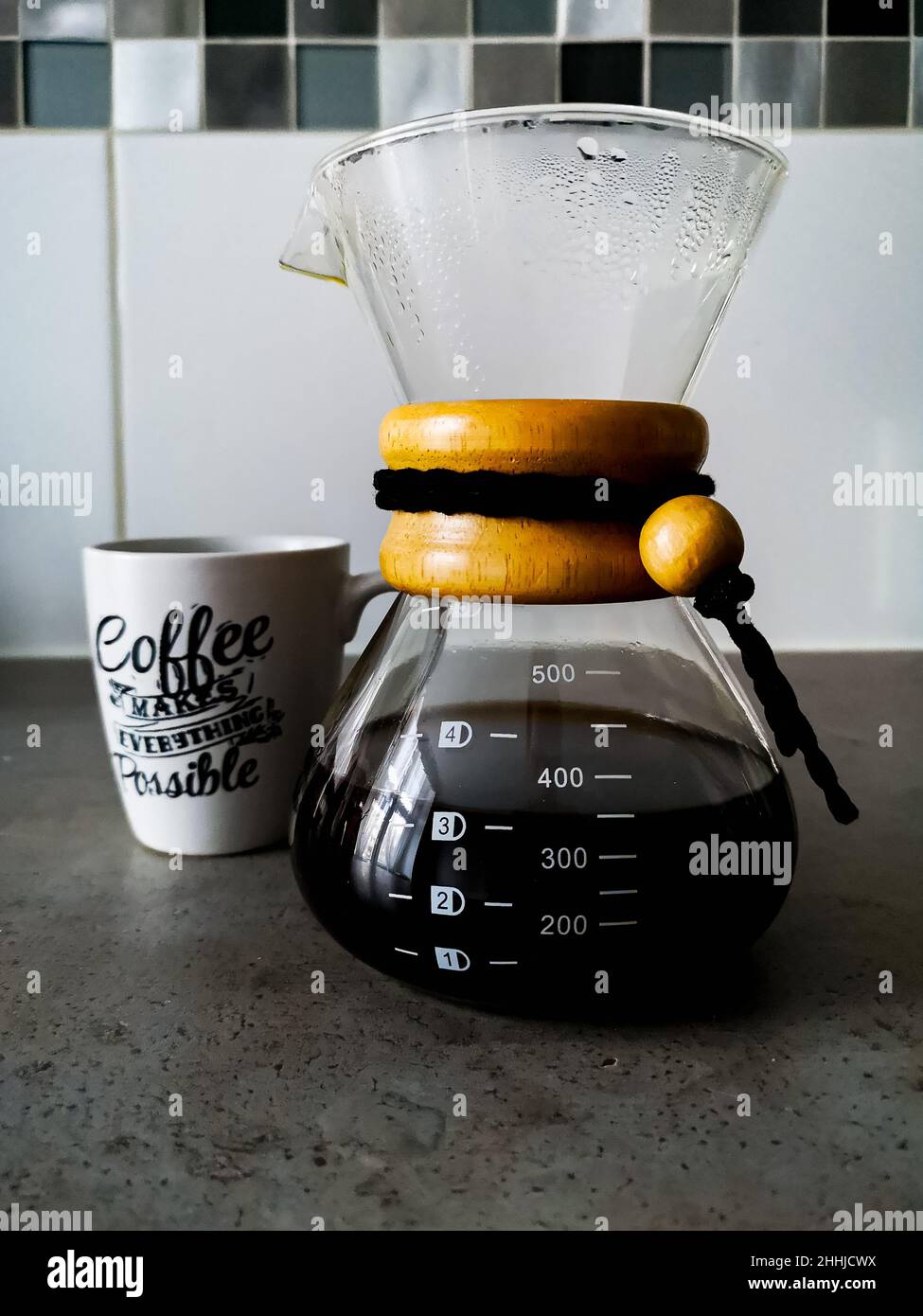 Un pot de café noir filtré de type chemex avec une tasse blanche avec des écrits calligraphiques pour le café Banque D'Images
