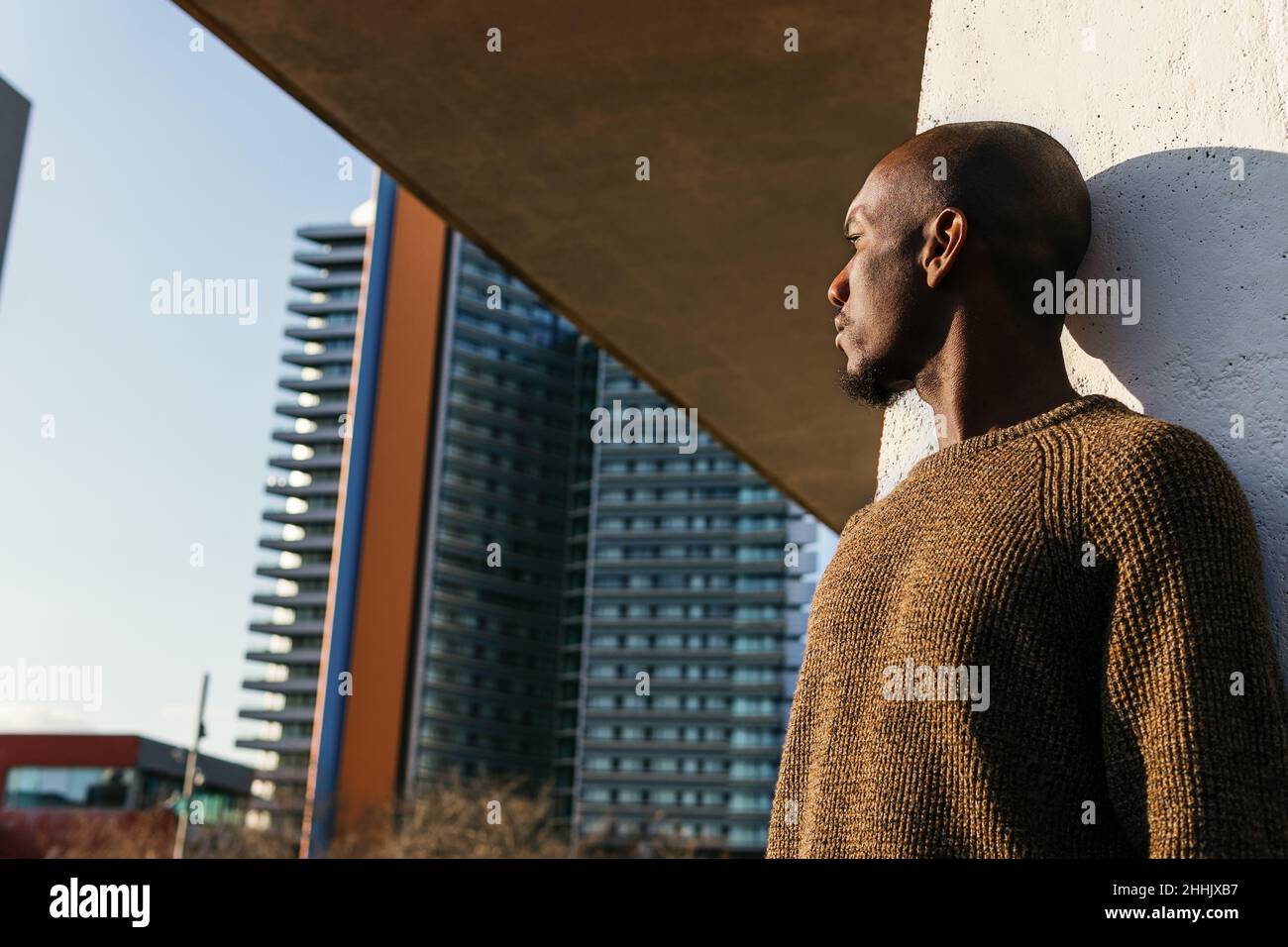 Un homme américain chauve d'Afrique sans émotion en tenue élégante debout près du mur sur la rue de la ville Banque D'Images