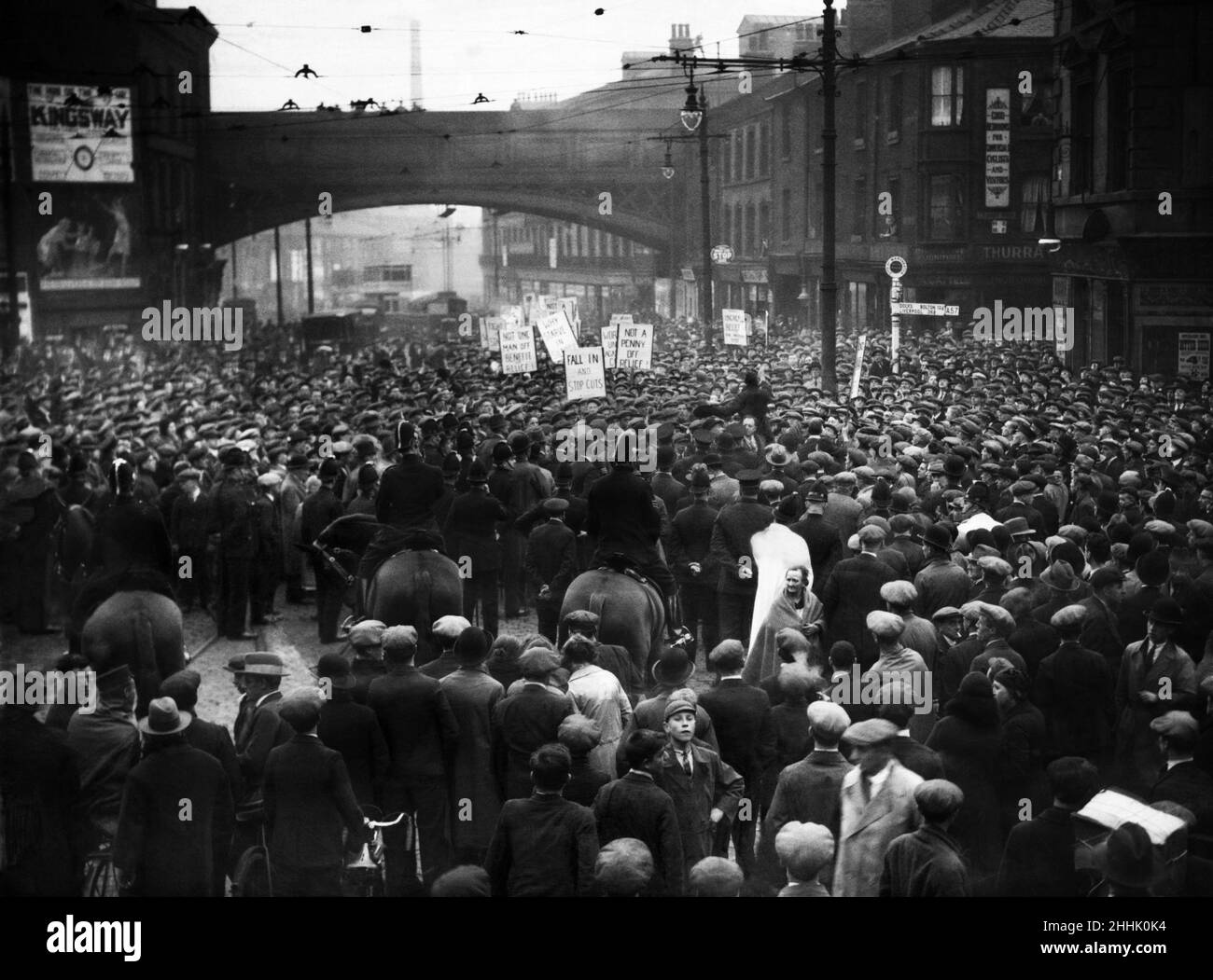La police regarde une manifestation de chômeurs organisée par le mouvement national des chômeurs (NUWM) descendre sur London Road Manchester pour protester contre les réductions des allocations chômage, des soins de santé, de la maternité et de la protection de l'enfance imposées aux chômeurs.Ils ont défilé sur Ashton Old Road depuis Openshaw, mais quand ils ont atteint la jonction de Downing Street et Fairfield Street, une rangée de policiers montés ont barré le chemin.Derrière les chevaux se trouvait une double rangée de la police des pieds et derrière eux une barricade de tramways, de bus à impériale et d'autres véhicules.7th octobre 1931 Banque D'Images