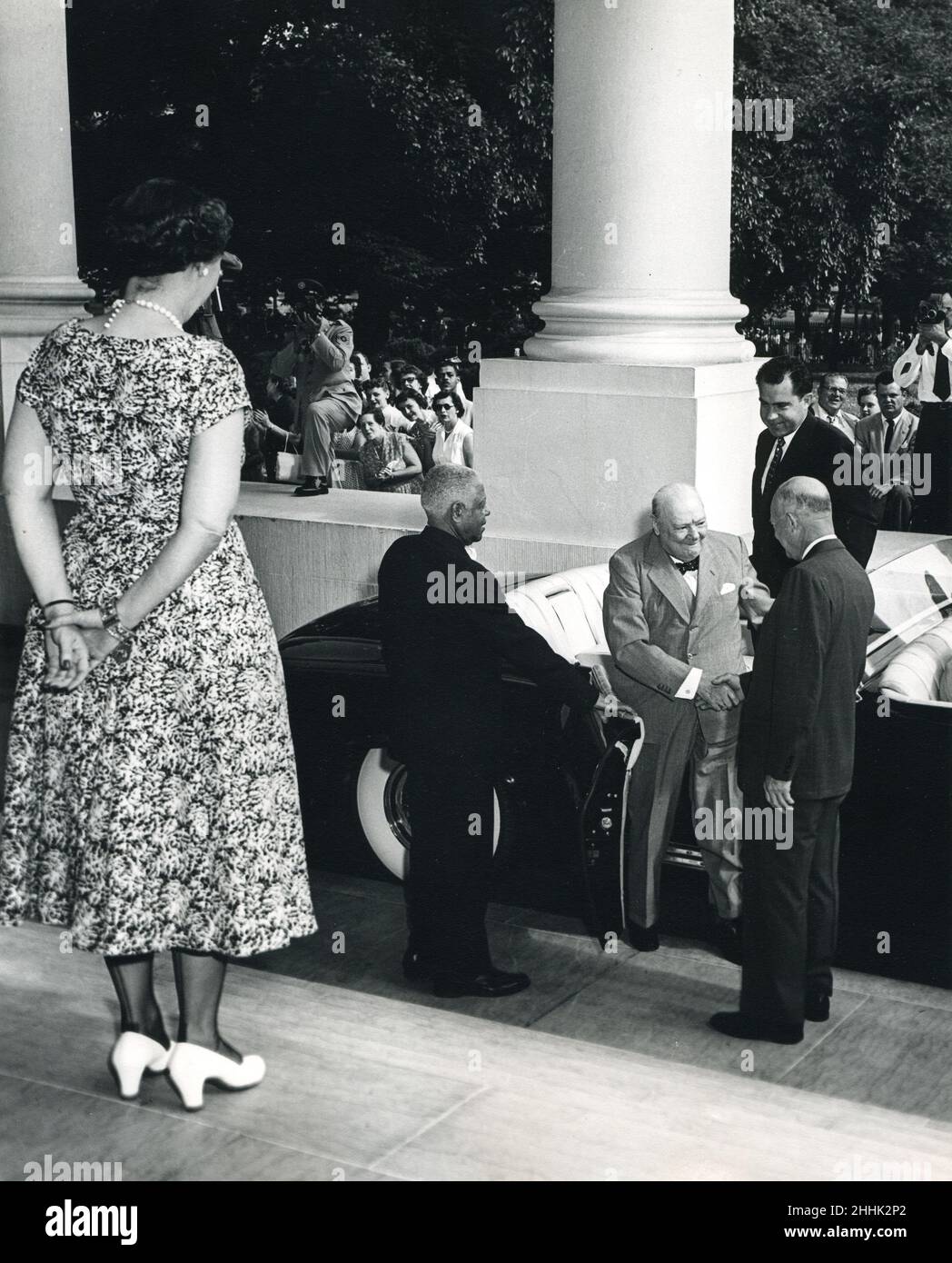 Washington, DC, le 25 juin 1954 - Mamie Eisenhower attend au sommet des marches alors que le président Dwight Eisenhower salue le Premier ministre Winston Churchill alors qu'il se trouve dans une limosine à la Maison Blanche.Le vice-président Richard Nixon attend derrière l'homme d'État britannique. Banque D'Images