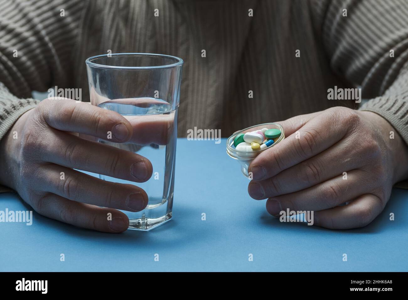 L'homme tient un verre d'eau et de pilules. Banque D'Images