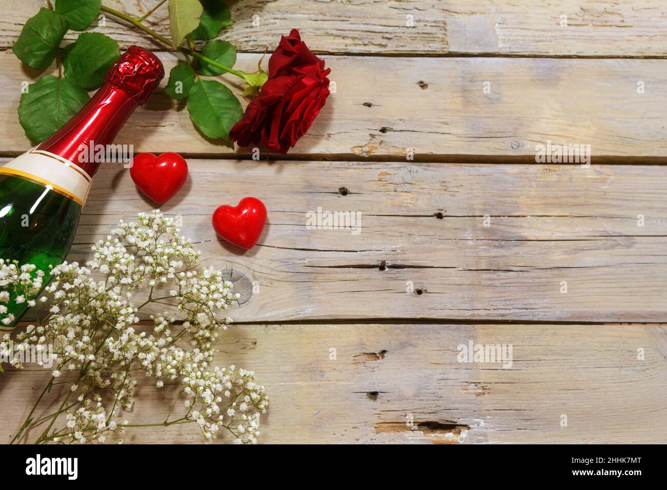 Invitation romantique avec champagne, rose rouge et deux coeurs sur fond rustique en bois, concept d'amour pour la Saint-Valentin, espace de copie, haut angle vi Banque D'Images