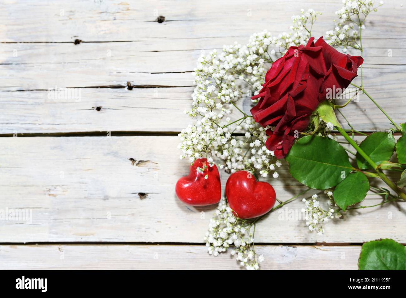 Rose rouge et deux coeurs sur des planches de bois rustiques peintes en blanc, carte de voeux romantique pour la Saint-Valentin ou la fête des mères, espace pour les copies, vue du dessus f Banque D'Images