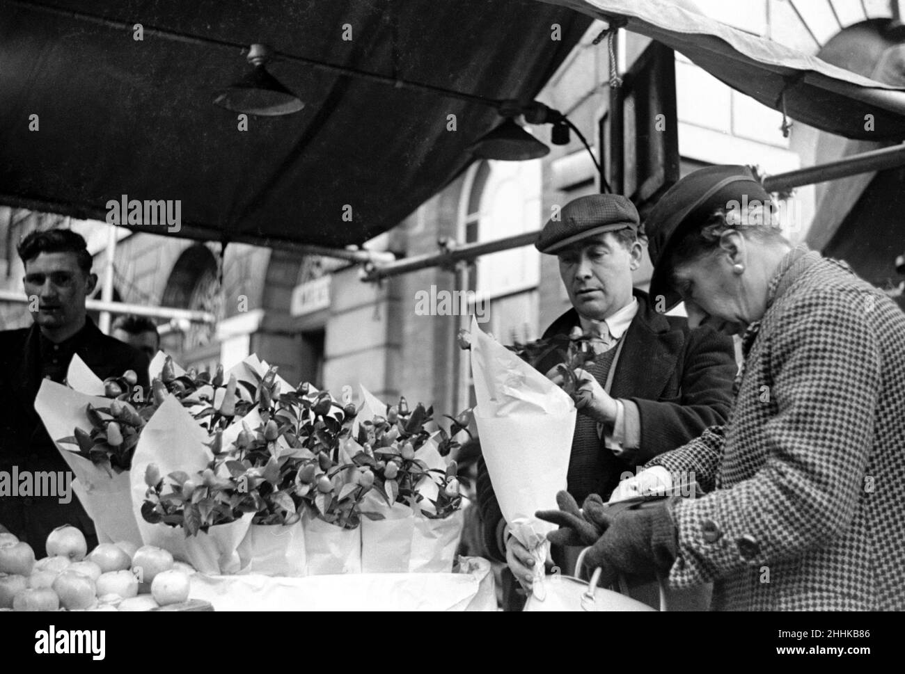 Le vendeur de fleurs au marché de Kingston vu ici servir un client .Vers 1936 Banque D'Images