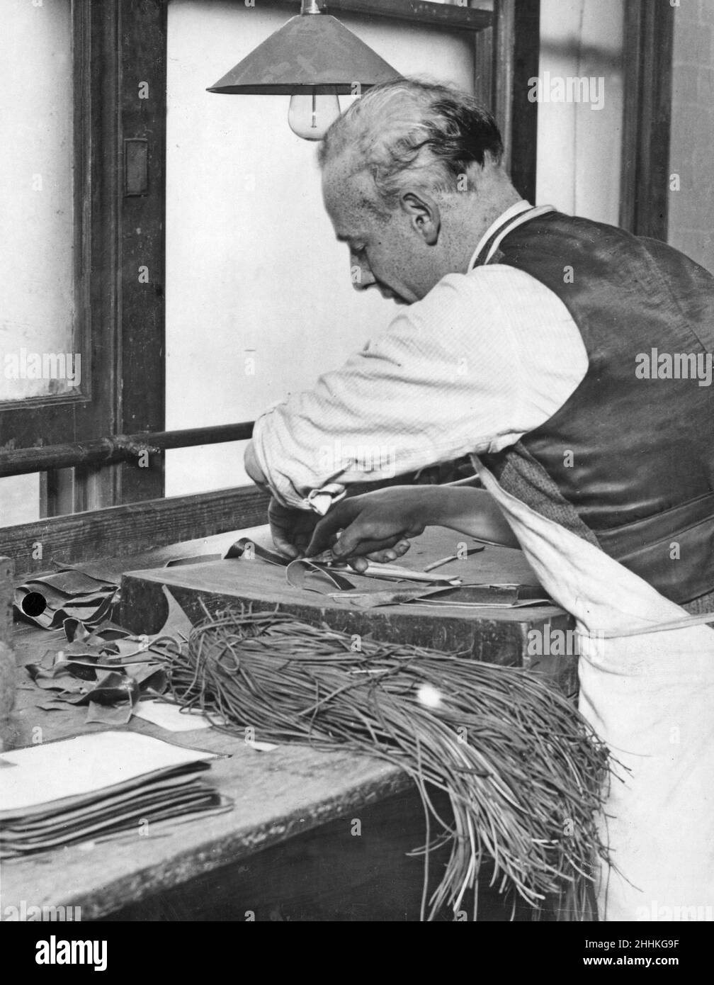 Un cutter de cuir qualifié réalise la première étape de la fabrication d'un sac à main en coupant le cuir à un modèle.9th octobre 1931 Banque D'Images