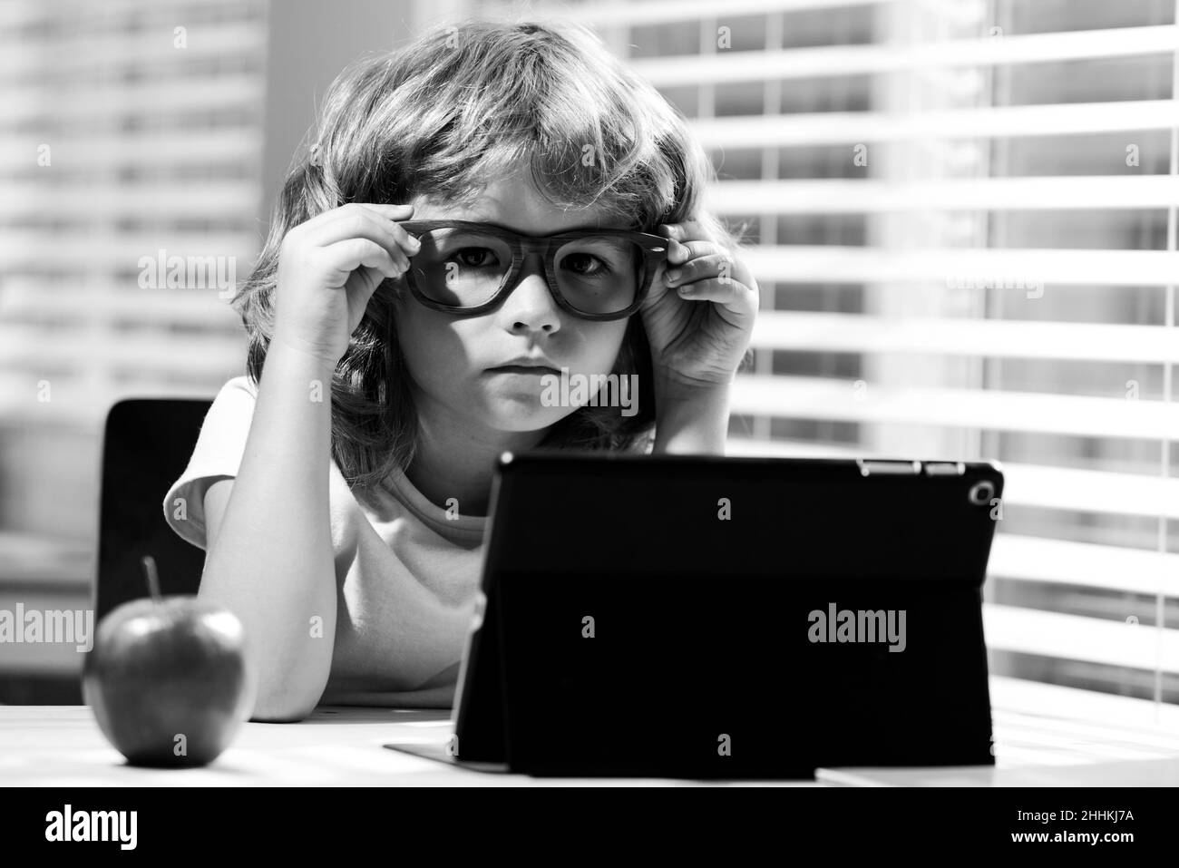 Enfant garçon dans des lunettes à l'aide d'une tablette et d'étudier en ligne avec l'enseignant d'appel vidéo à la maison, homeschooling, l'apprentissage à distance E-learning, homeschool et Banque D'Images