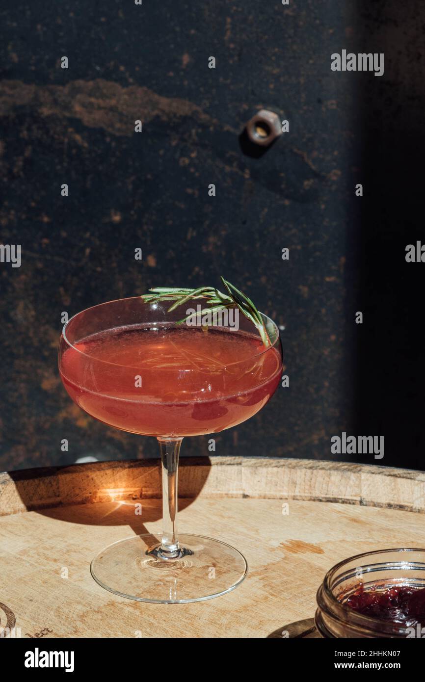 cocktail de confiture rouge en verre coupé au soleil avec garniture au romarin Banque D'Images