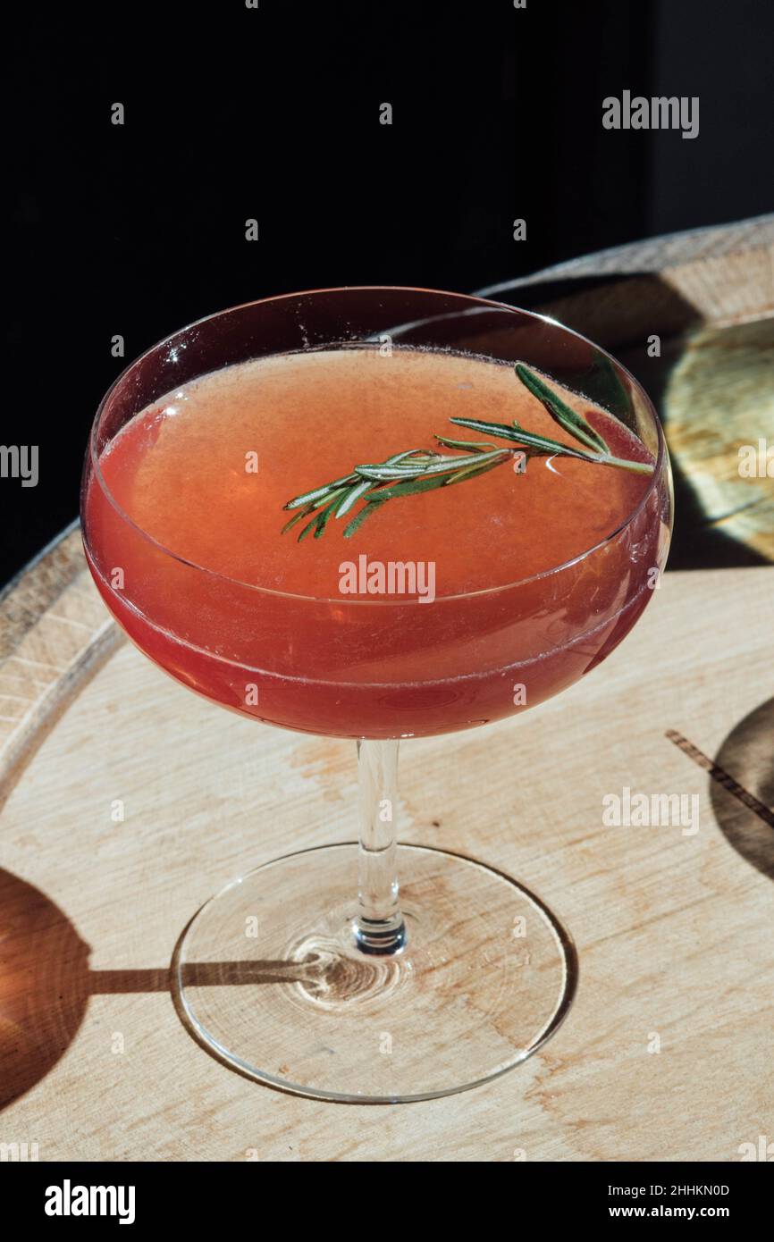 cocktail de confiture rouge en verre coupé au soleil avec garniture au romarin Banque D'Images