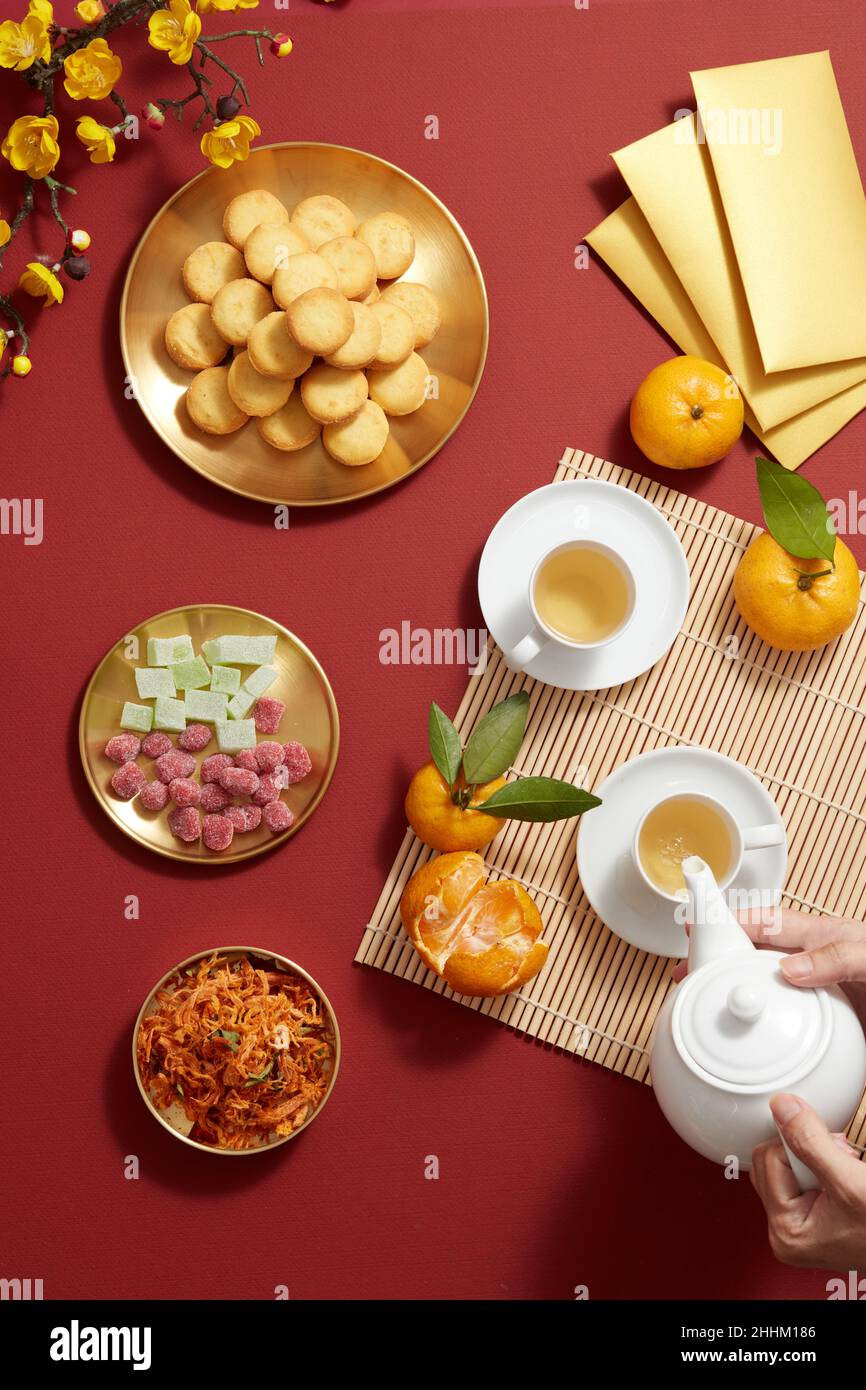 Vacances du nouvel an chinois avec confiture de bonbon orange mandarin,  théière de pomme de terre frit, fleur et biscuit de poche rouge dans un  plat doré, photographie Tet vacances Photo Stock -