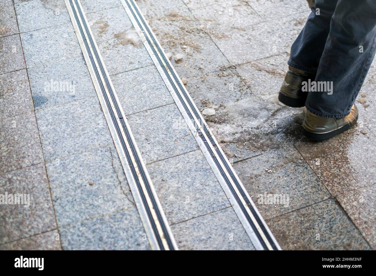 jambes dans des chaussures d'hiver marchant sur des marches glissantes, tir d'hiver en plein air Banque D'Images