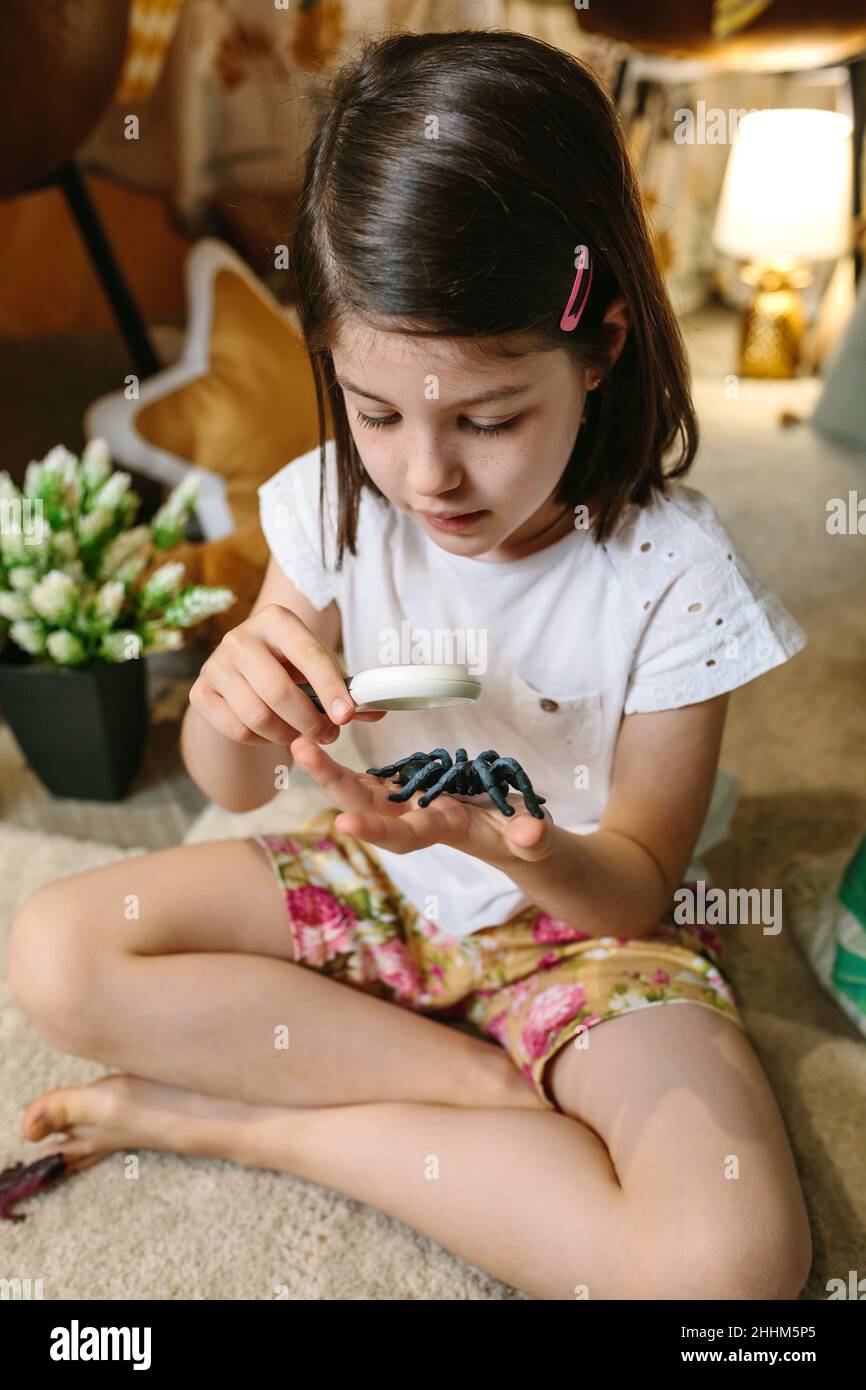 Fille jouant observant les insectes de jouet avec une loupe Banque D'Images