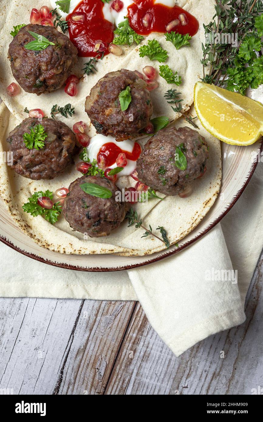 Boulettes de viande traditionnelle maison de bœuf et d'agneau avec pain arabe, sauce tomate, grenade et herbes aromatiques.Nourriture halal Banque D'Images