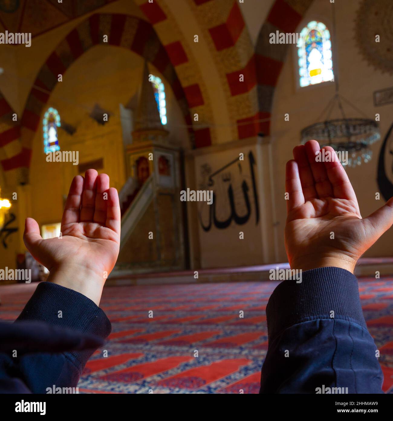 L'origine islamique.Homme musulman priant en levant la main dans la mosquée.Texte du nom d'Allah sur les murs.Ramadan ou photo de fond islamique.Ed Banque D'Images