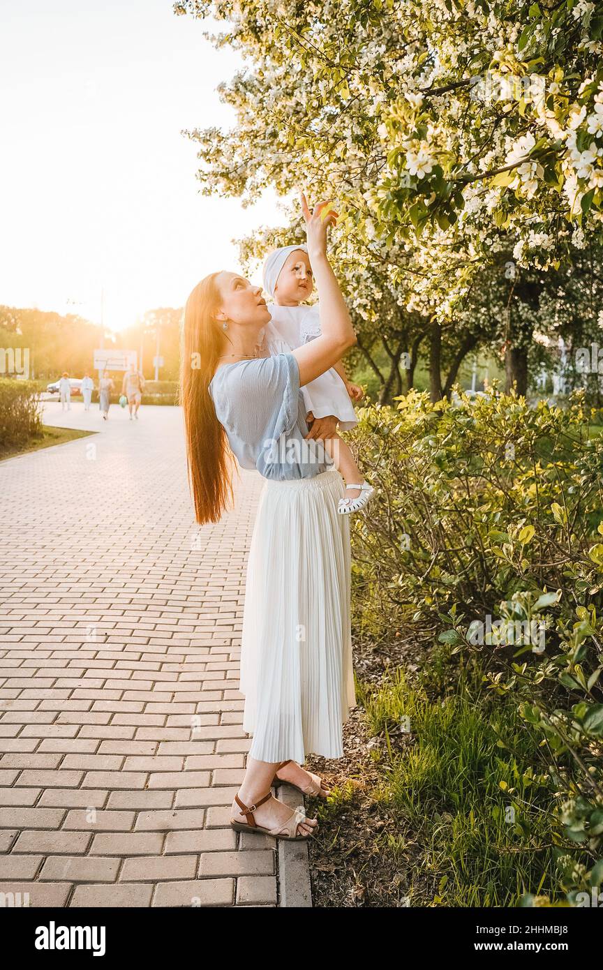 Mère et petite fille près d'un pommier en fleurs.Lumière du coucher de soleil, concept de printemps. Banque D'Images