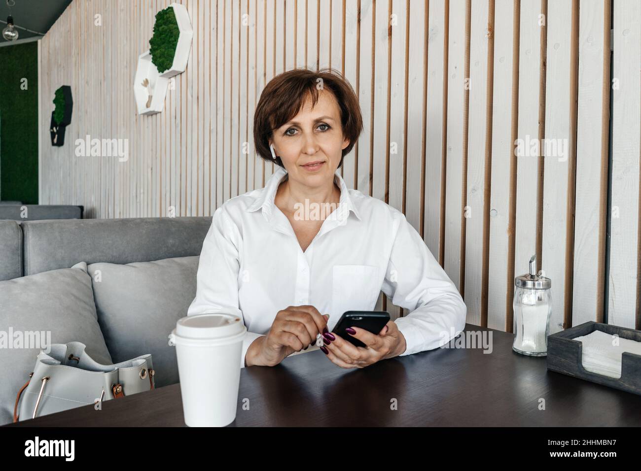 Femme d'affaires senior travaillant dans un café. Travailler à distance avec un téléphone portable. Banque D'Images