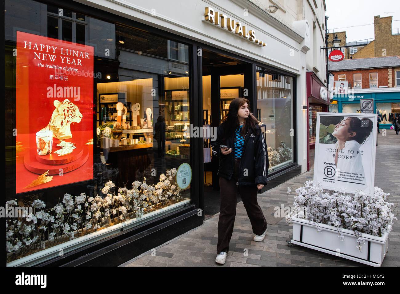 Kingston upon Thames, Royaume-Uni.24th janvier 2022.Une personne qui tient un téléphone portable passe devant un magasin et affiche un message du nouvel an lunaire heureux.Le Banque D'Images