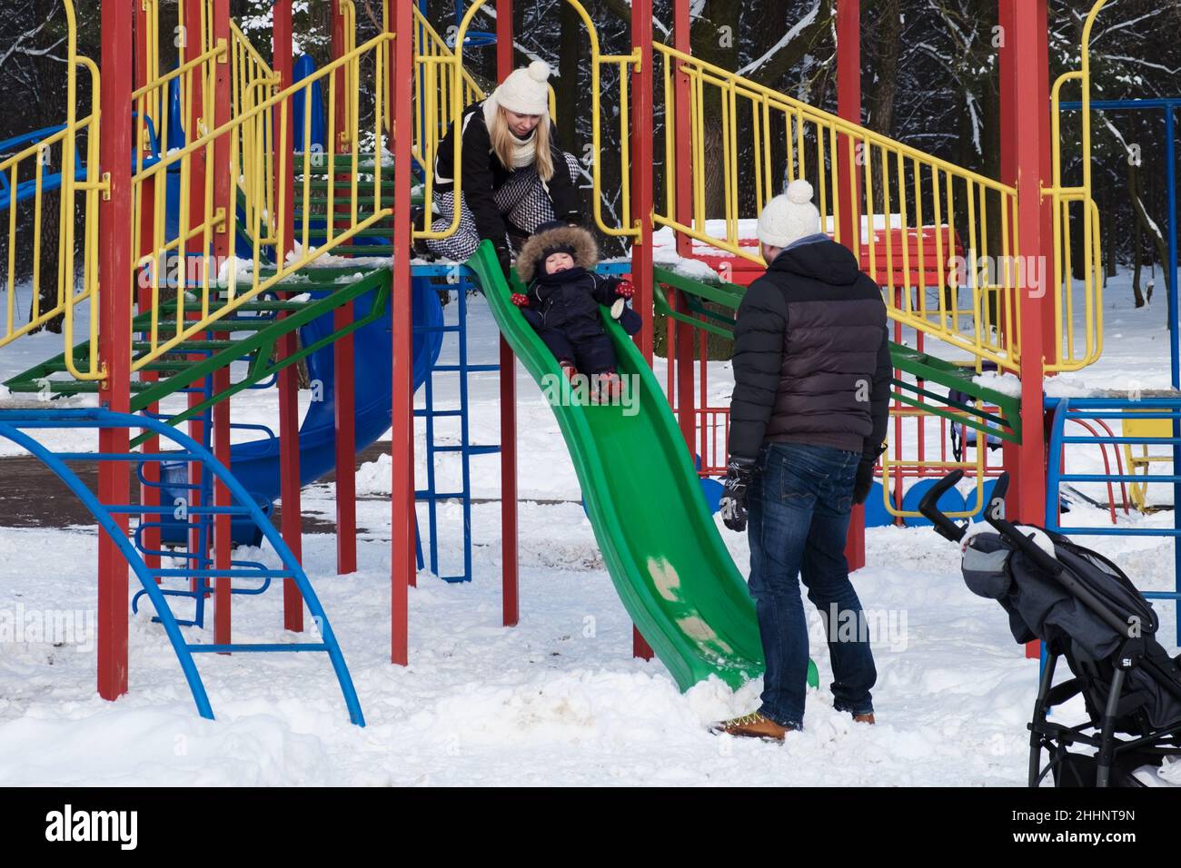 Parents avec un bébé sur l'aire de jeux en hiver.Maman, papa, bébé.Minsk (Bélarus) Banque D'Images