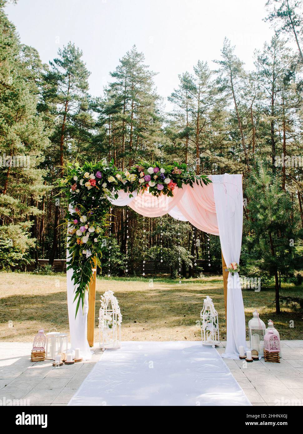 Cérémonie de mariage en plein air dans la pinède d'été.Arc de mariage avec  décoration florale et tissu rose Photo Stock - Alamy