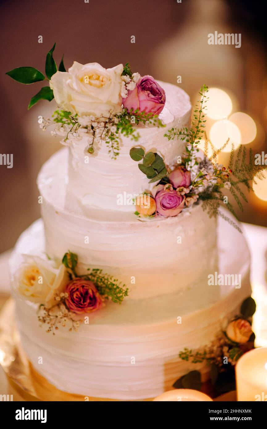 Gâteau de mariage blanc à trois niveaux.Gâteau blanc crémeux décoré de fruits de mesh, de baies et de fleurs. Banque D'Images