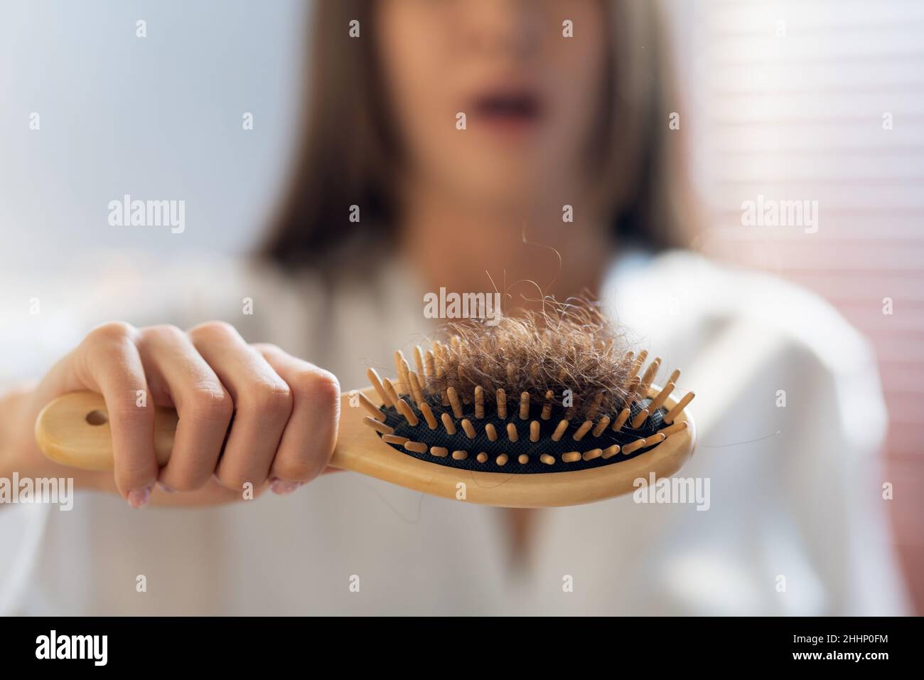 Concept de perte de cheveux.Femme inquiète tenant Comb plein de cheveux tombés après le brossage Banque D'Images