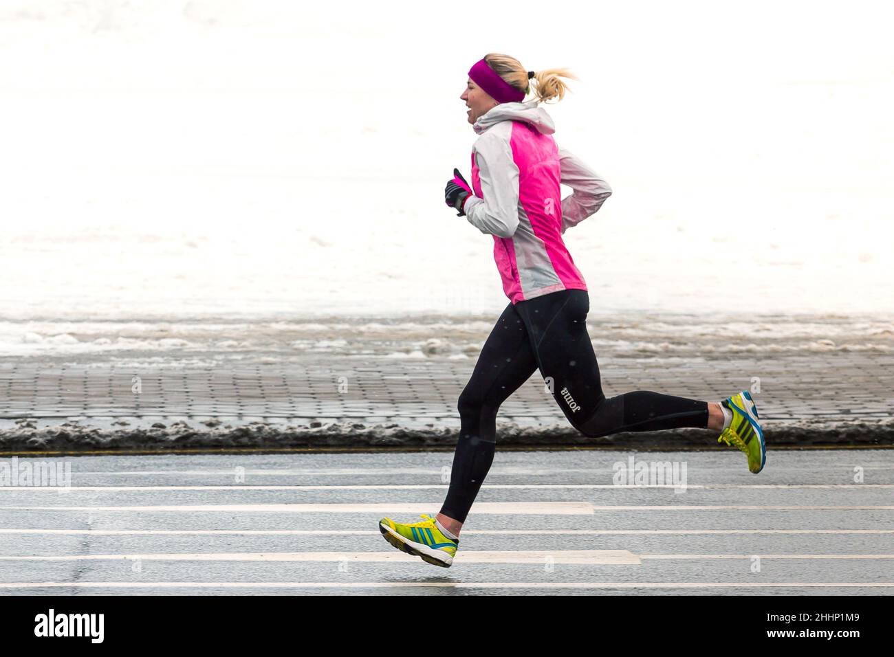 Une athlète féminine qui court en hiver en plein air par temps froid et enneigé.Gros plan indiquant la vitesse et le mouvement. Banque D'Images