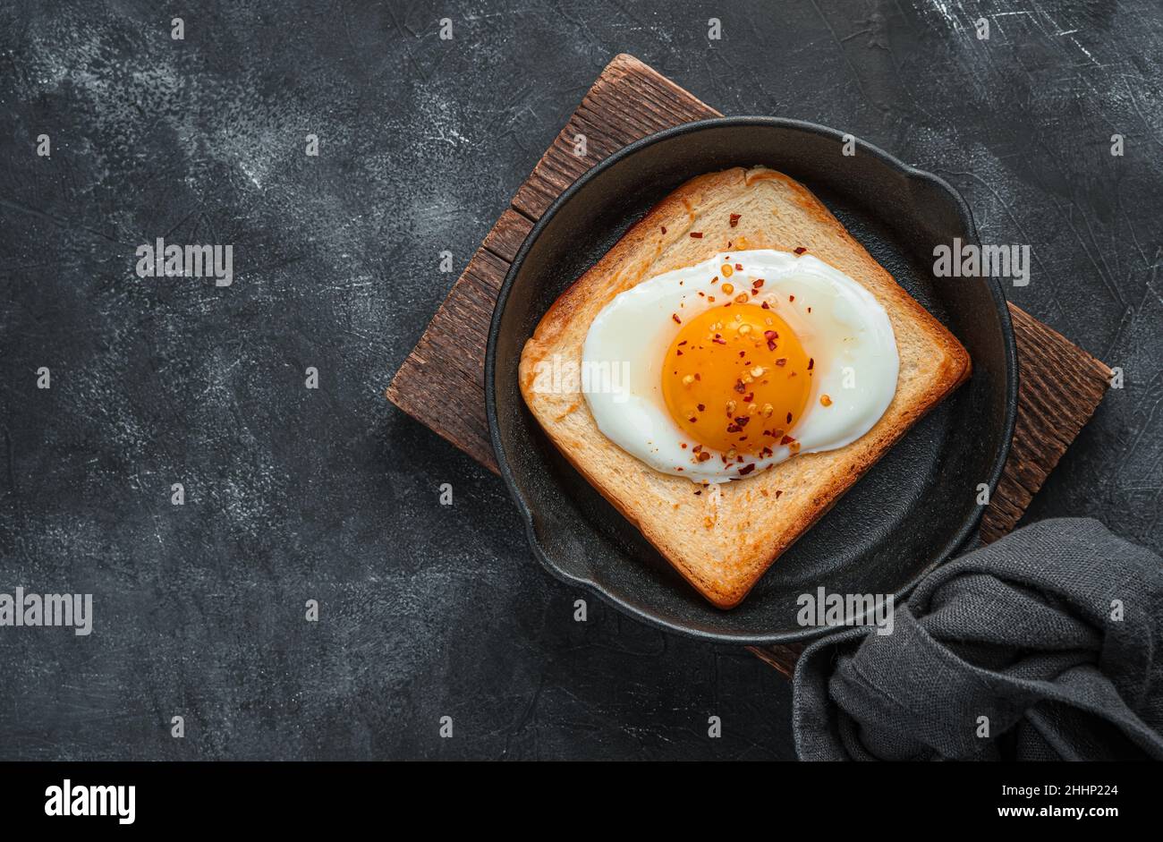 Petit déjeuner frais avec œufs frits dans une poêle sur fond sombre. Banque D'Images