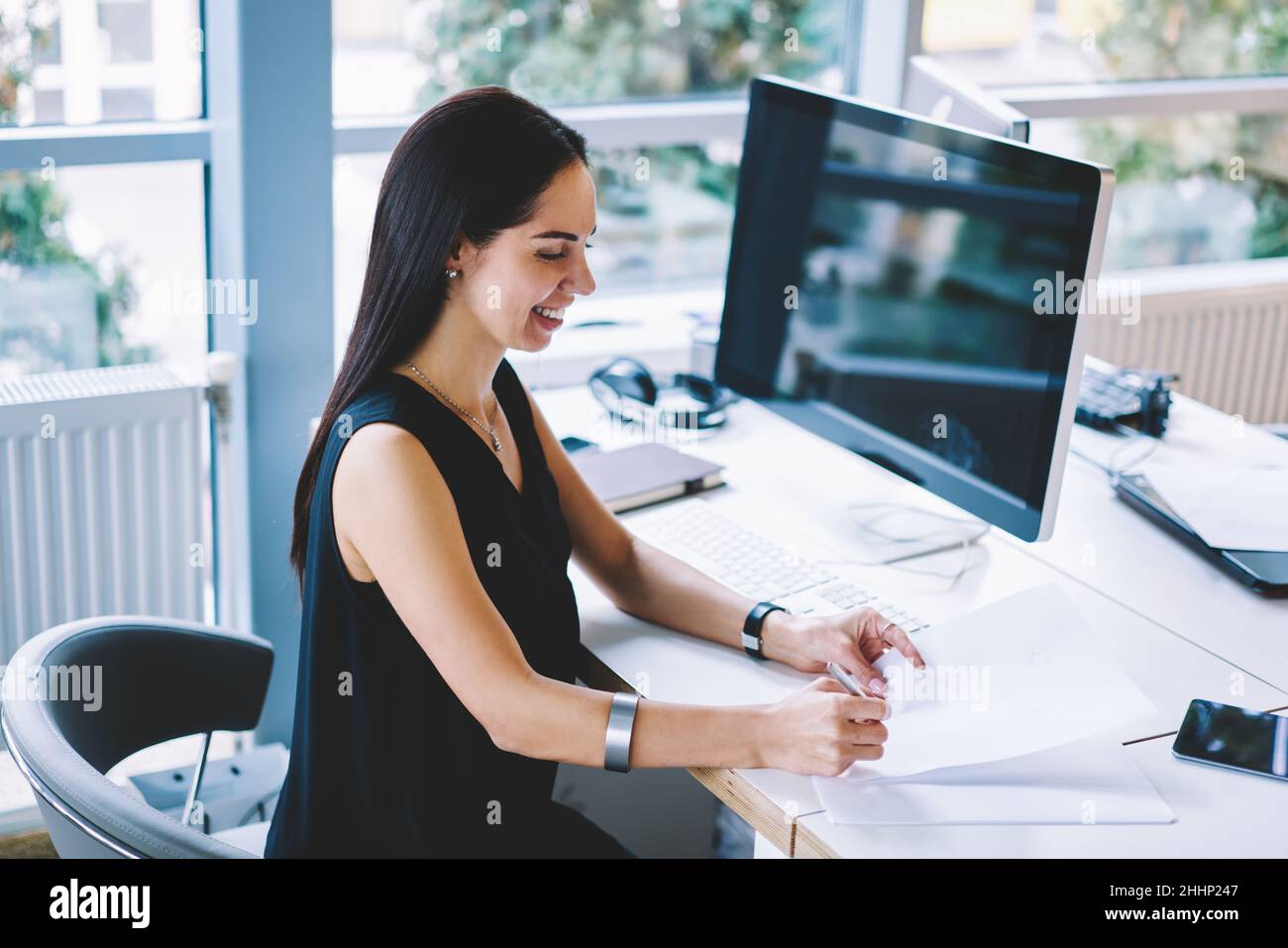 Femme souriante travaillant avec des documents au bureau Banque D'Images