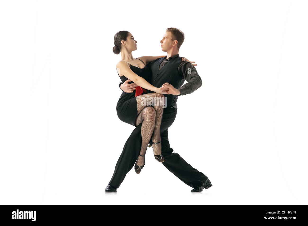 Grace et belles danseurs, jeune couple dansant le tango argentin isolé sur fond blanc de studio.Artistes en costumes de scène noire Banque D'Images