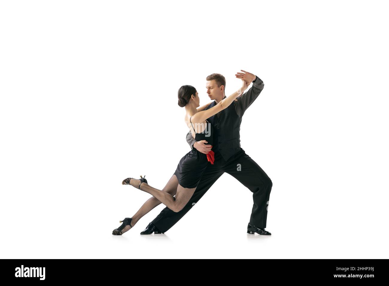 Portrait dynamique de jeunes danseurs flexibles dansant le tango argentin isolé sur fond blanc de studio.Artistes en costumes de scène noire Banque D'Images