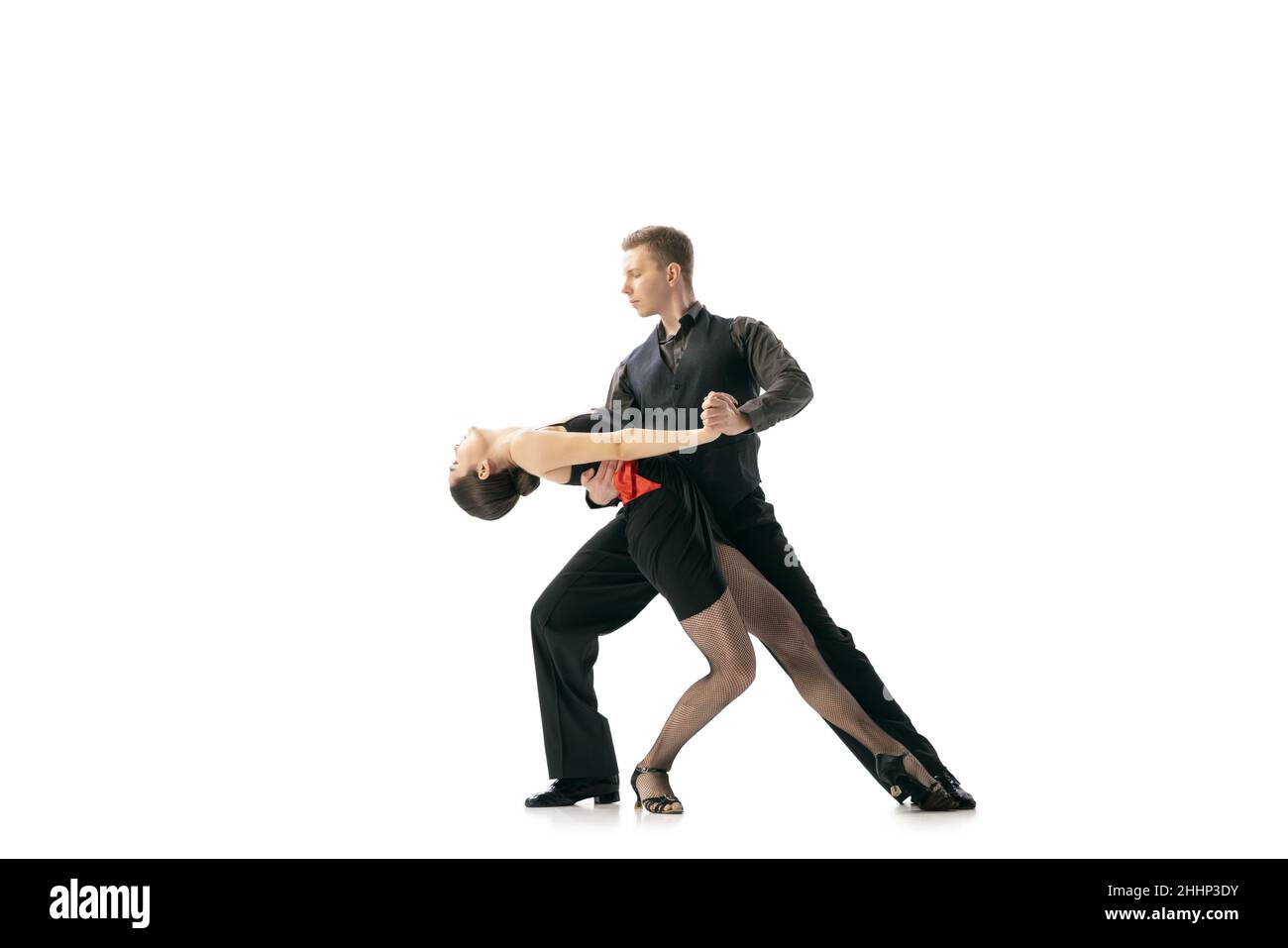 Grace et belles danseurs, jeune couple dansant le tango argentin isolé sur fond blanc de studio.Artistes en costumes de scène noire Banque D'Images