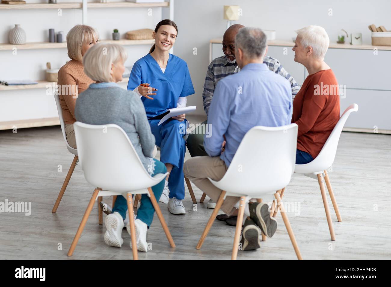 Jeune femme gaie psychologue discutant avec des personnes âgées Banque D'Images