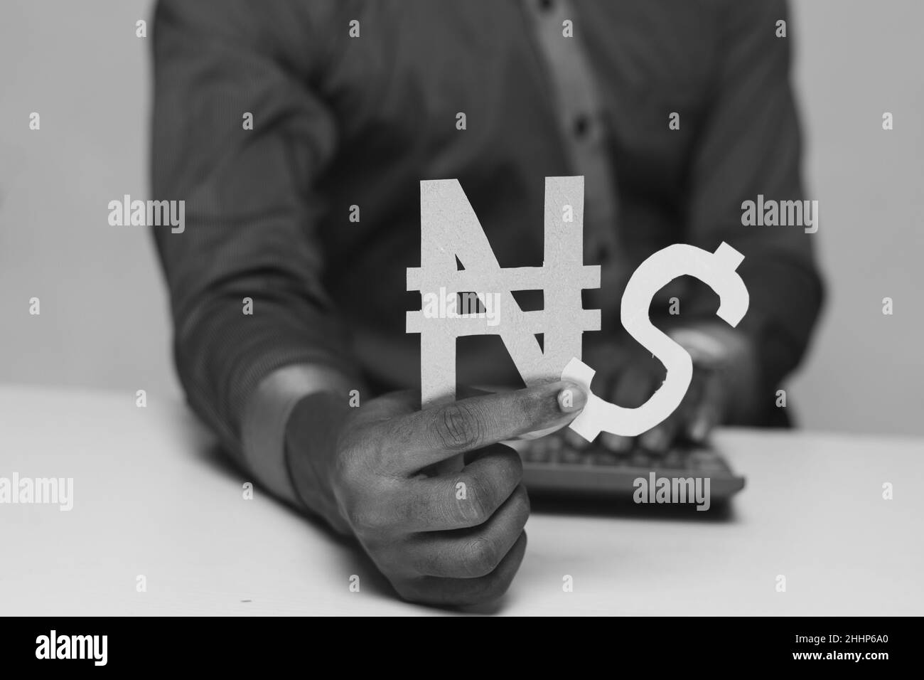 Photo en niveaux de gris d'un homme d'affaires noir tenant des signes dollar et naira Banque D'Images