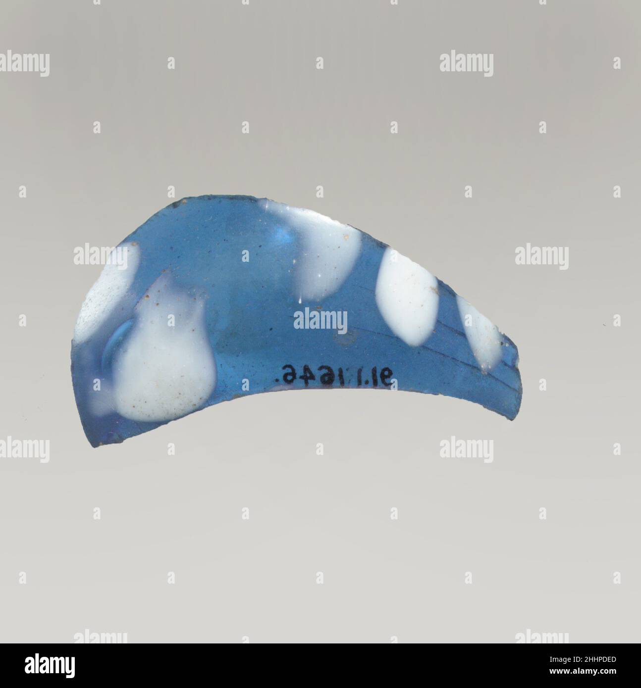 Fragment de verre 1st Century A.D. Roman Translucent bleu cobalt, avec blanc opaque.fragment de corps avec côté bombé.Décoration de grosses breloques irrégulières à l'extérieur.deux grandes fissures internes parallèles traversant le fragment dans le sens de la longueur; poli à l'extérieur, avec piqûres de bulles de surface; bords altérés;Léger effet irisé sur l'extérieur.probablement une partie d'une bouteille fermée plutôt qu'une tasse ouverte.Fragment de verre.Romain.1st siècle A.D..Verre ; soufflé avec des breloques marrées appliquées.Début de l'Impériale.Verre Banque D'Images