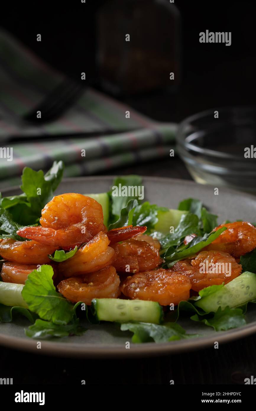 Salade fraîche aux crevettes grillées, concombres et arugula, servie sur une assiette, image verticale. Banque D'Images