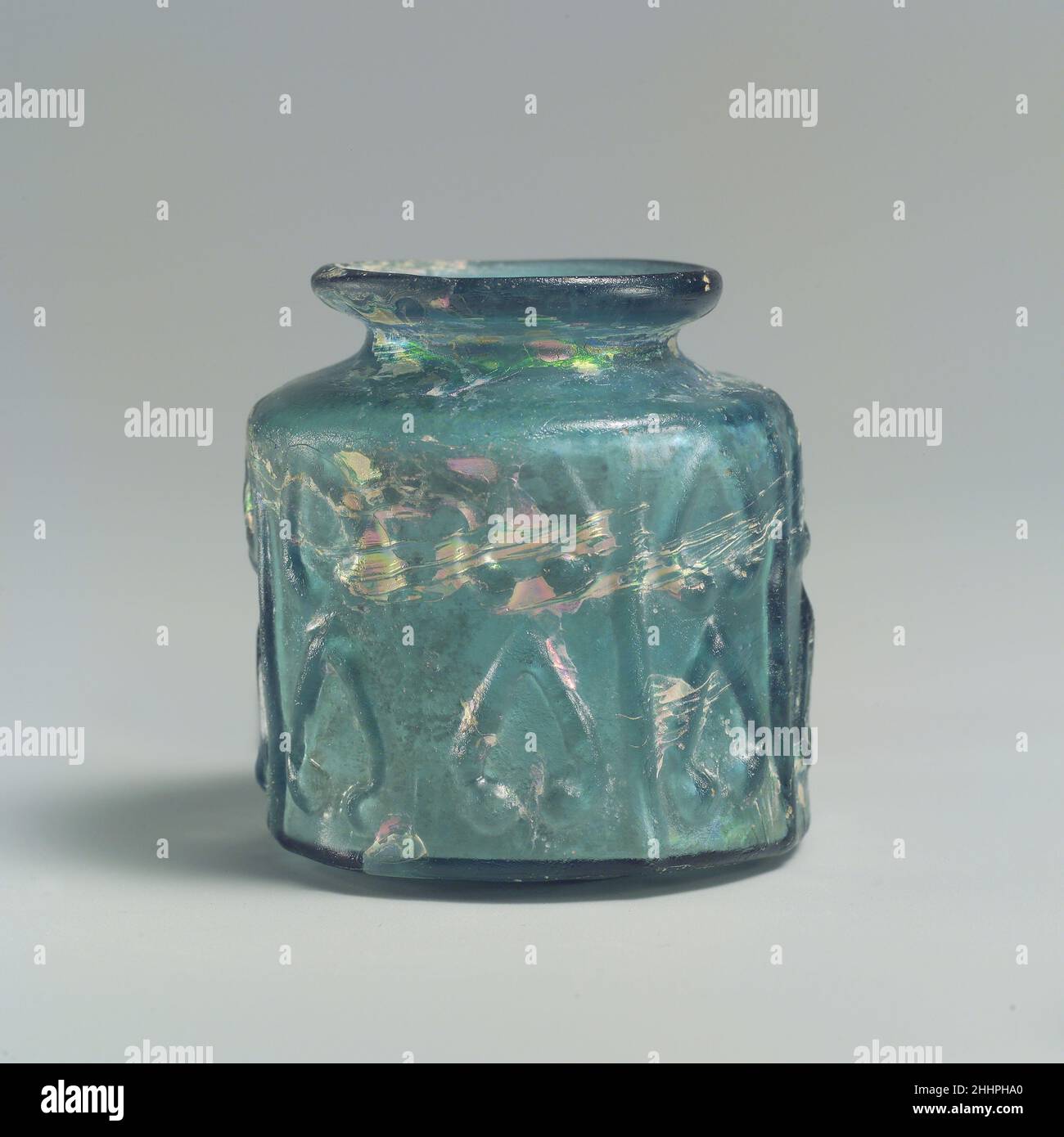 Petit pot 9th–10th Century la décoration moulée de ce pot en verre bleu verdâtre comprend des paires de palmettes simples disposées l'une au-dessus de l'autre dans huit compartiments verticaux étroits.Ensemble, ils suggèrent à la fois une datation du neuvième au dixième siècle et une provenance de l'Irak pour ce petit pot.L'impression d'un aigle avec des ailes étalées sous la base, qui n'est généralement pas visible, peut être un timbre d'usine.Petit pot.9th–10th siècle.Verre, bleu verdâtre ; moulé.Attribué probablement à l'Irak.Verre Banque D'Images