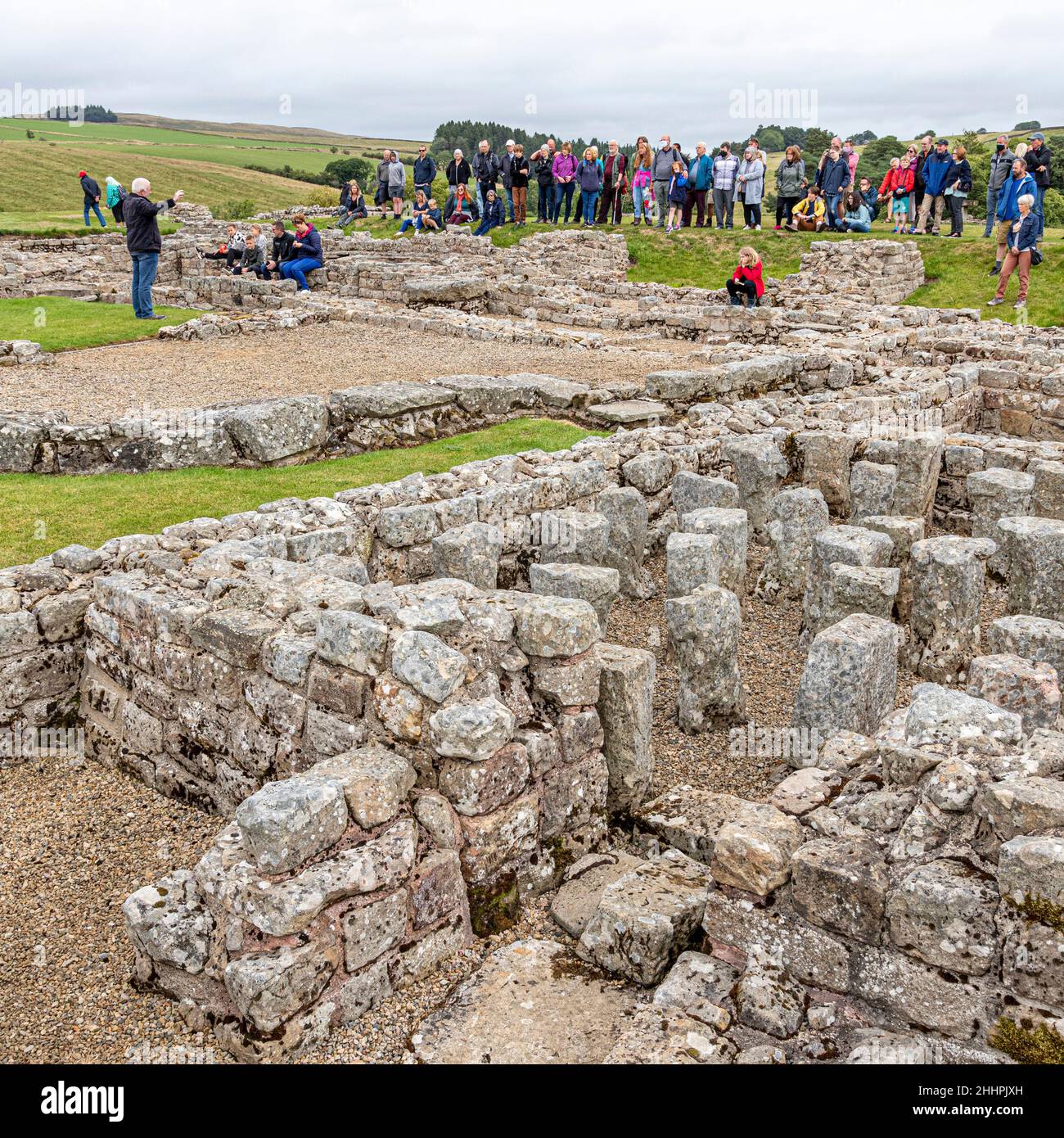 Groupe ayant une visite guidée des ruines du fort auxiliaire romain de Vindolanda à Chesterholm, Northumberland, Royaume-Uni Banque D'Images