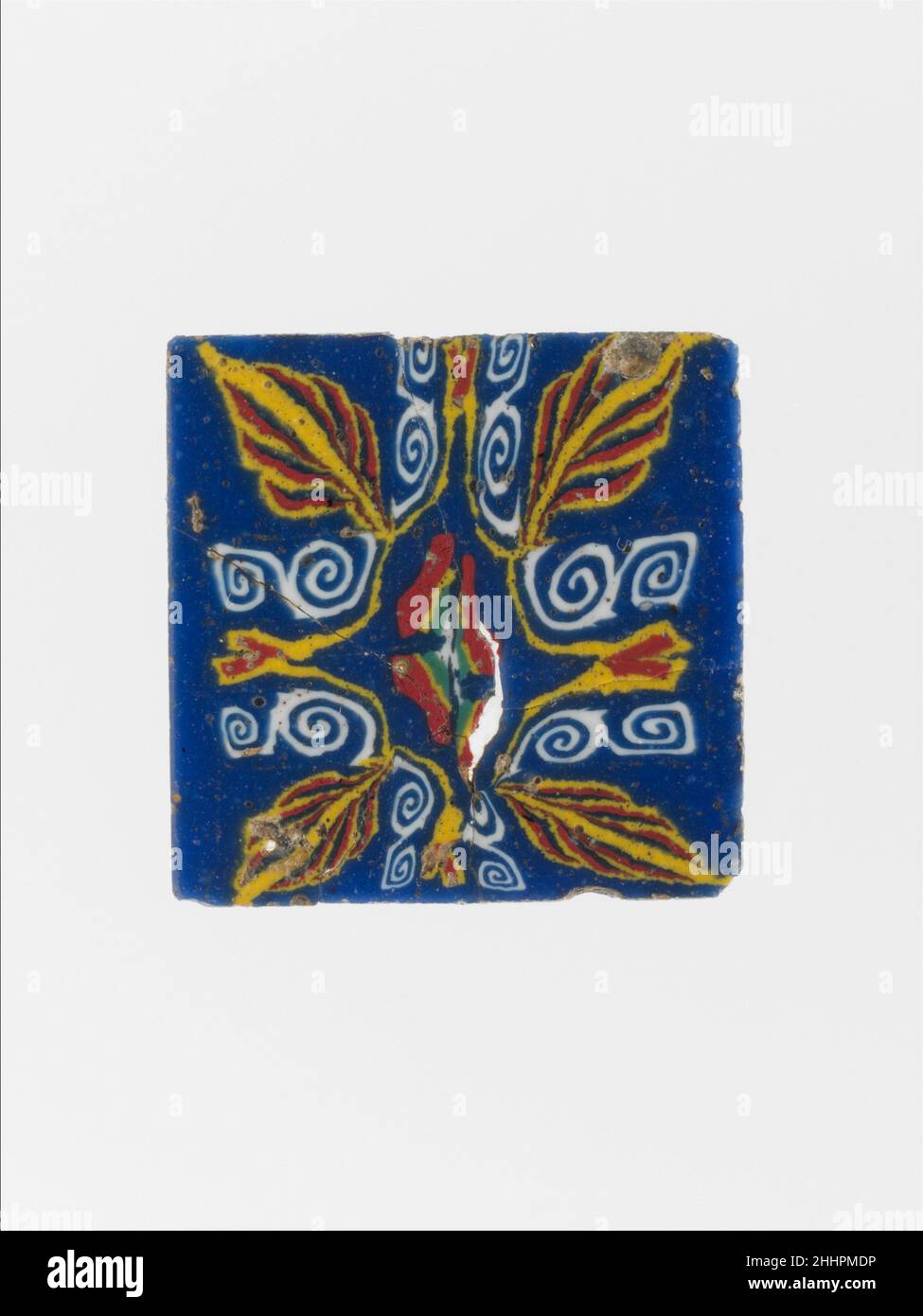 Incrustation en mosaïque de verre 1st siècle C.-B.–1st siècle A.D. Egyptien, Ptoléméen ou romain semi-opaque bleu cobalt; décoration en blanc opaque, jaune, rouge et vert grisâtre. Carré, mince,Plaque plate, avec bords légèrement biseautés.motif symétrique lotus et palmette disposé autour d'une rosette centrale compressée à quatre pétales, avec une grande palmette à chaque coin avec des volutes en spirale doubles formant un cadre à une petite fleur de lotus déformée de chaque côté.cassée et réparée avec de petits trous et des fissures;Côté supérieur rectifié et poli; bulles de surface piquées, altération sur les bords et arrière.carré, plusieurs co Banque D'Images