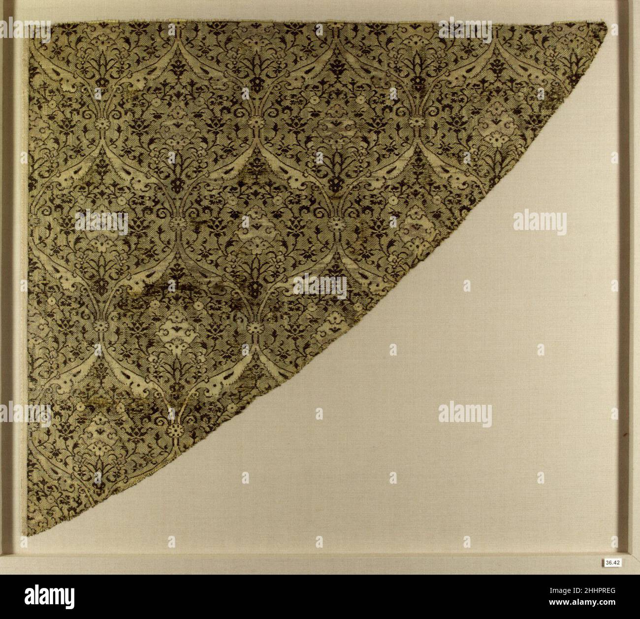 Fragment textile fin 15th siècle le fil métallique confère une qualité chatoyante à ce fragment textile triangulaire décoré d'un cadre ogival.Les médaillons ogivaux ont été utilisés dans divers médias, y compris les reliures, le travail des métaux et les textiles, pendant la période Timuride.Le kitabkhana (atelier impérial et bibliothèque) a défini des tendances décoratives dans les arts du livre qui ont ensuite été traduits dans ces médias, générant un style artistique cohésif.Fragment textile fin 15th siècle.Soie, fil métallique ; lampas.Attribué à l'Iran.Textiles-tissés Banque D'Images